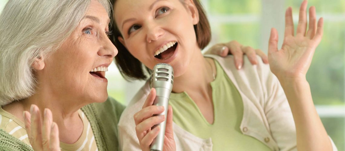 Senior woman with daughter singing on microphone